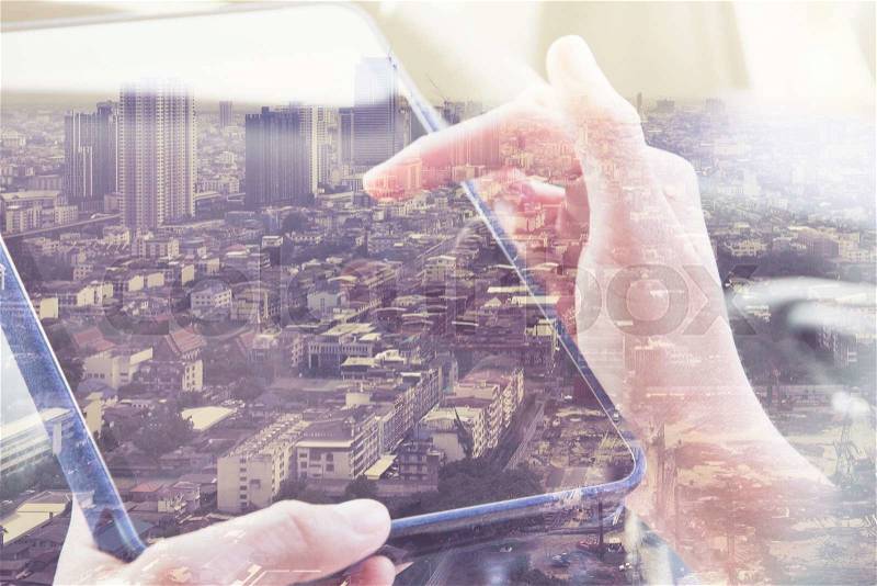 Using digital tablet double exposure and and cityscape background. Business technology concept, stock photo