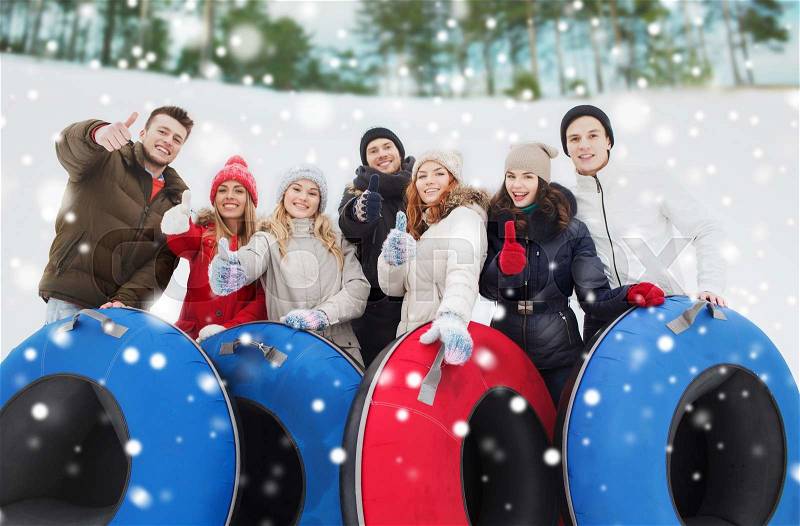 Winter, leisure, sport, friendship and people concept - group of smiling friends with snow tubes showing thumbs up outdoors, stock photo