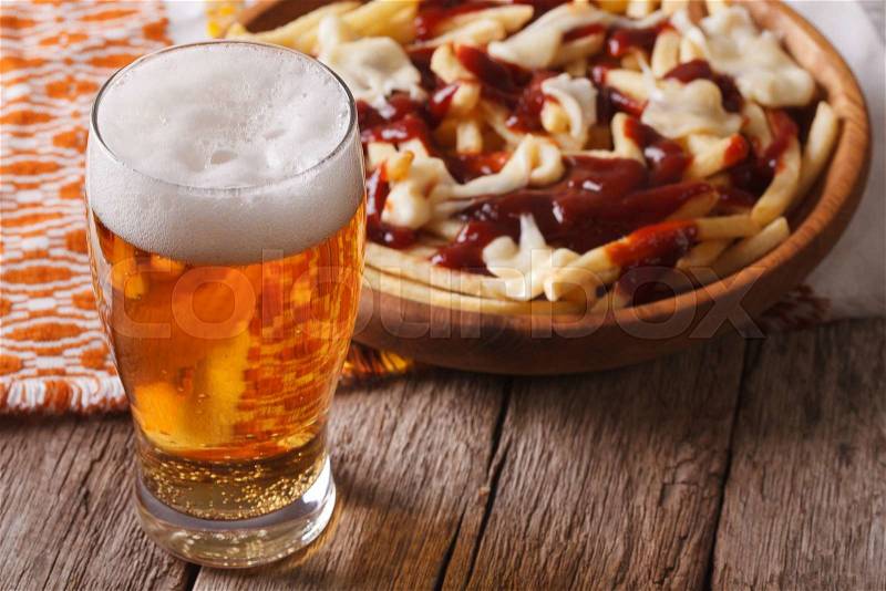 Canadian food: beer and fries with sauce close-up on the table. horizontal , stock photo