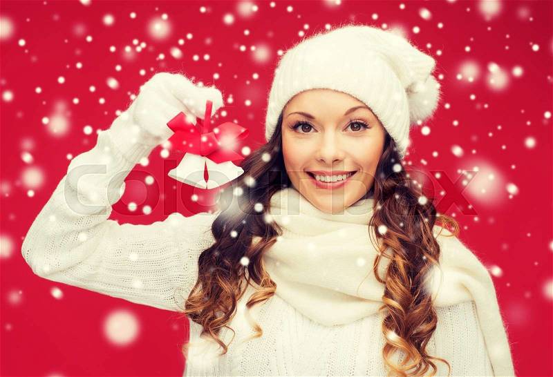 Christmas, x-mas, winter, happiness concept - smiling woman in mittens and hat with jingle bells, stock photo