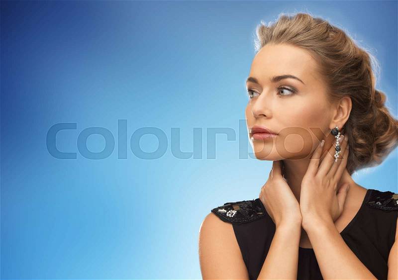 People, holidays and glamour concept - beautiful woman wearing earrings over blue background, stock photo