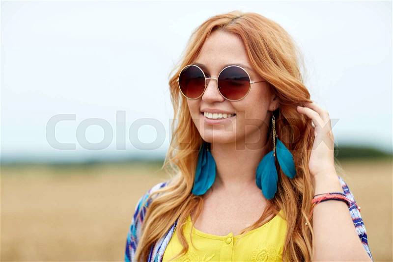Nature, summer, youth culture and people concept - smiling young redhead hippie woman in sunglasses outdoors, stock photo