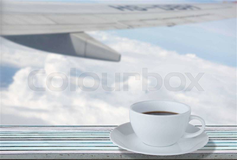 Air plane over blue sky and coffee cup on vintage wooden plank, stock photo