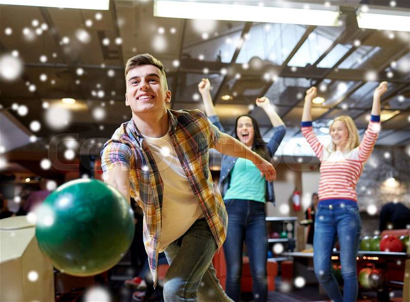 People, leisure, sport and entertainment concept - happy young man throwing ball in bowling club at winter season, stock photo