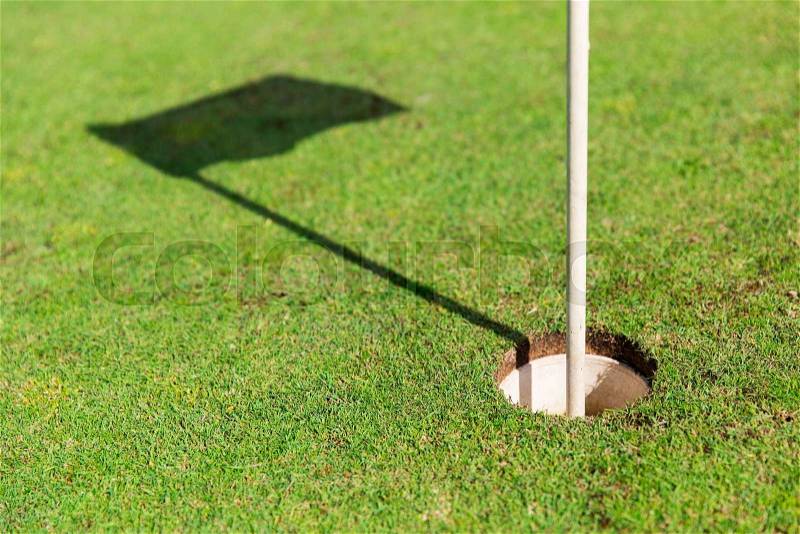 Game, entertainment, sport and leisure concept - close up of flag mark in hole on golf field, stock photo