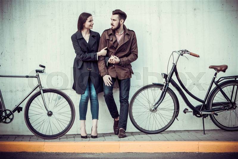 Young couple with a bicycle opposite the city , stock photo
