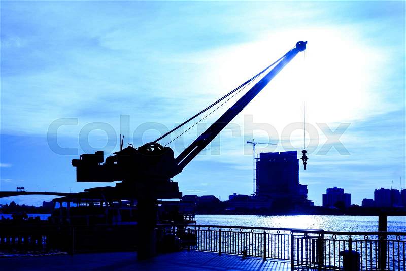 Blue silhouette crane hanging lift machinery at port with sunset in Bangkok, Thailand, stock photo