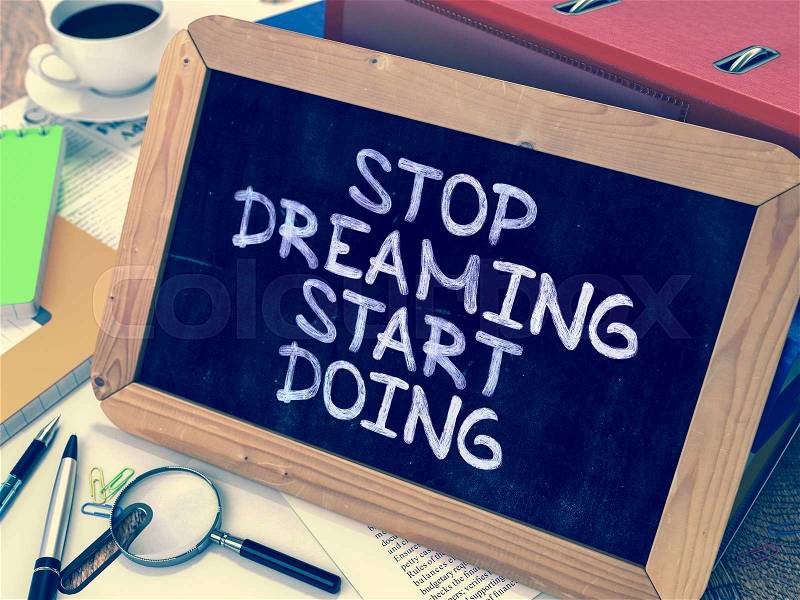 Stop Dreaming Start Doing. Motivational Quote Hand Drawn on Chalkboard on Working Table Background. Blurred Background. Toned Image, stock photo