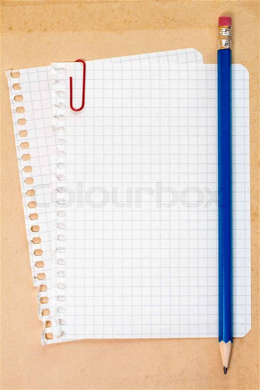 Checked notepad paper and pencil on cardboard background, stock photo