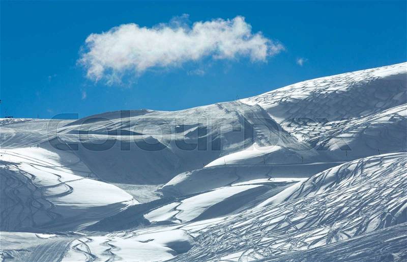 Hillside freaked ski tracks and lonely cloud in the blue sky. Winter Austria, stock photo
