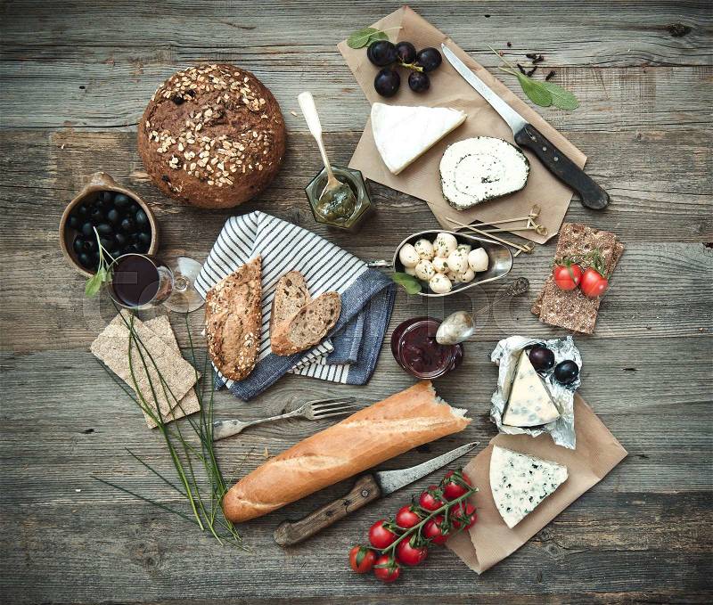 French food on a wooden background. Different types of cheese, wine and other ingredients on a wooden table, stock photo