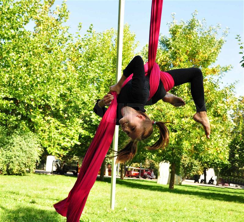 Outdoor activity of cheerful child training on aerial silks or ribbons. Childhood, sports, active lifestyle concept, stock photo