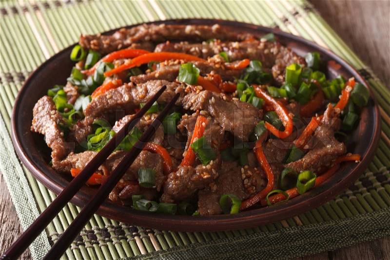 Asian cuisine: slices of beef fried with sesame and carrot close-up on a plate. horizontal , stock photo