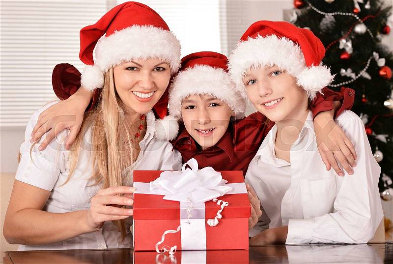 Cute mom and her kids in santa hats, stock photo