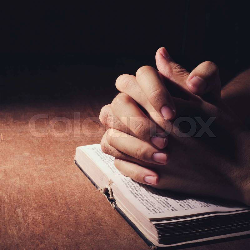 Praying hands with bible on the wooden desk background, stock photo