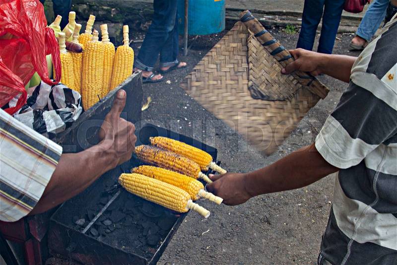 Asian man roasts and sells corn on street near beach.Delicious tasty healthy food, stock photo