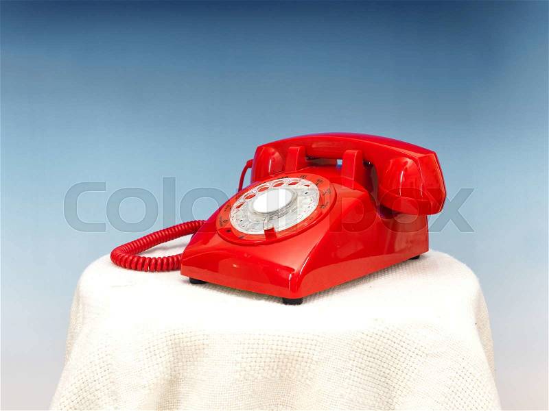 A close up photo of a red rotary phone, stock photo