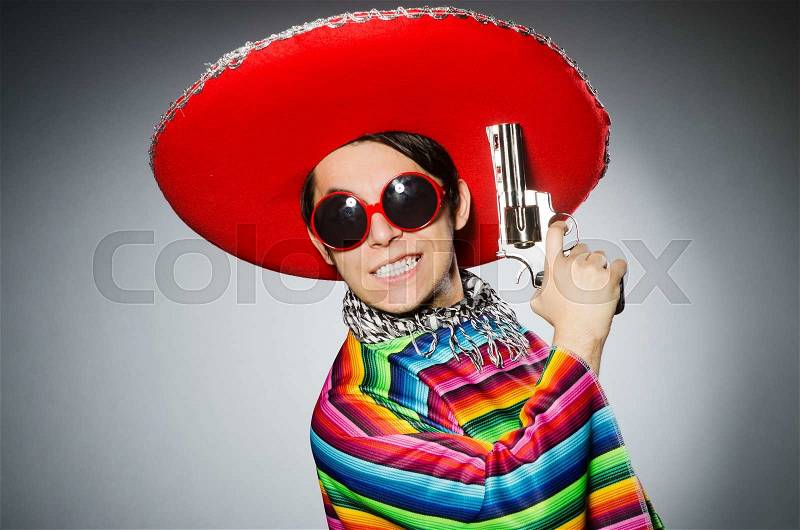 Man in vivid mexican poncho holding handgun against gray, stock photo