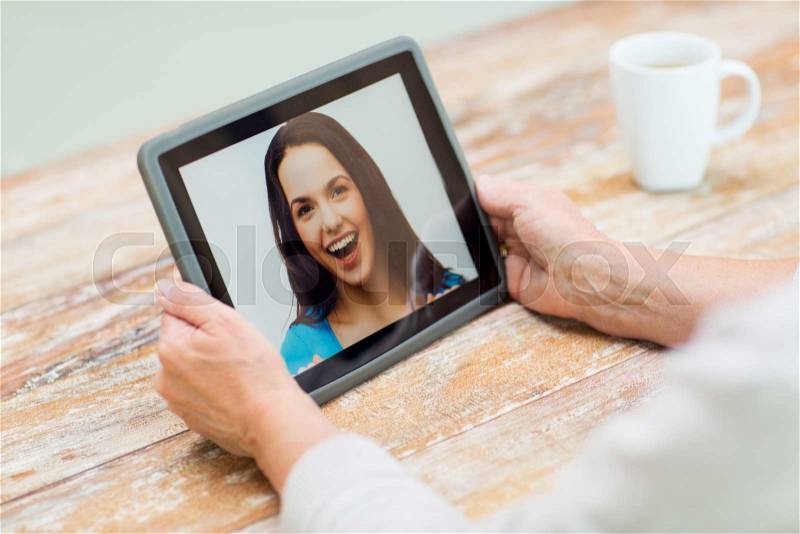Technology, age, memories and people concept - happy senior woman with tablet pc computer viewing photo or having video chat with granddaughter at home, stock photo