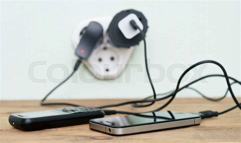 Smart phone and mobile phone charging with cable on the wooden table, stock photo