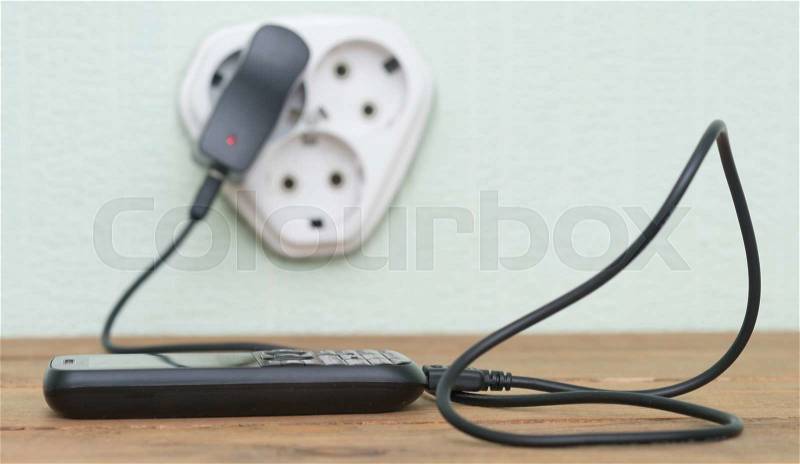 mobile phone charging with cable on the wooden table, stock photo