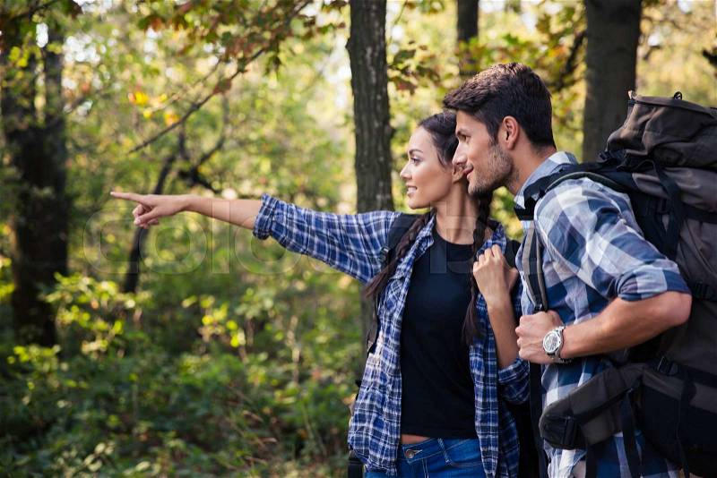 Portrait of a woman pointing on something to her boyfriend in forest, stock photo
