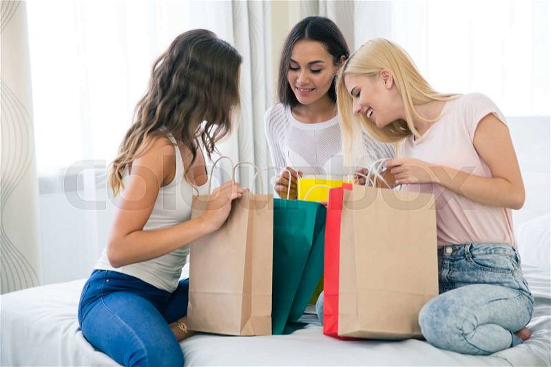 Portrait of a cheerful three girlfriends with many shopping bags at home, stock photo