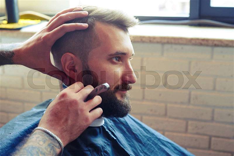 Portrait of handsome man in barbershop. barber shaving man with straight razor , stock photo
