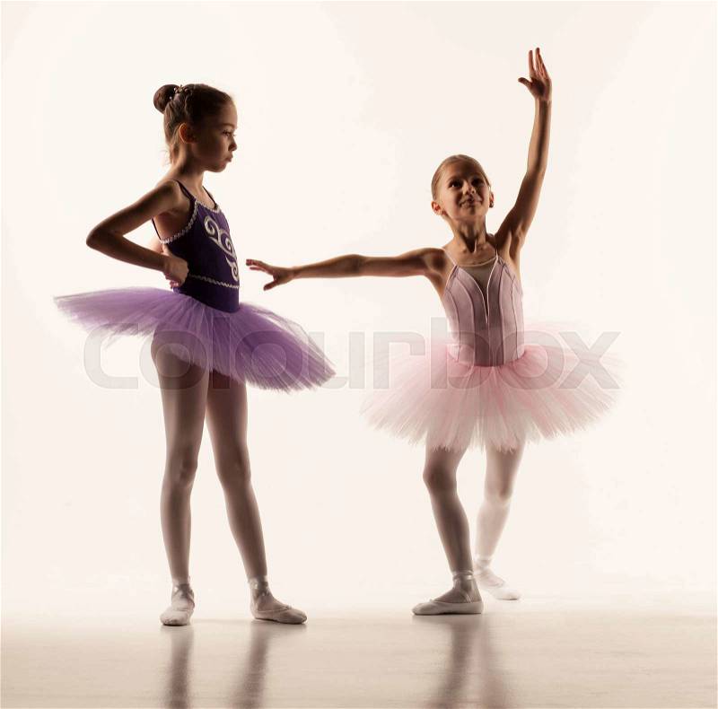 The two little ballet girls in tutu standing against white studio , stock photo