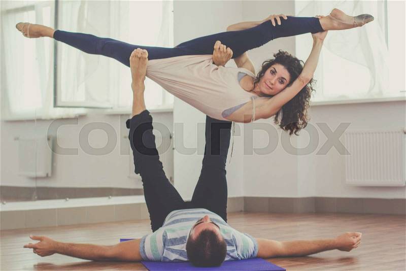 Young sportive couple boy and girl are practicing yoga exercises in the studio, stock photo
