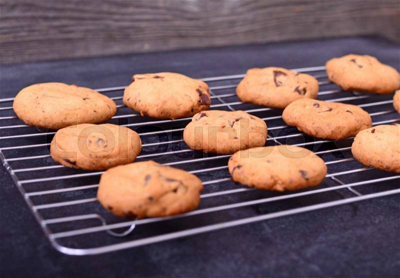 Home baked chocolate cookies on cooling rack on black background - close up, stock photo