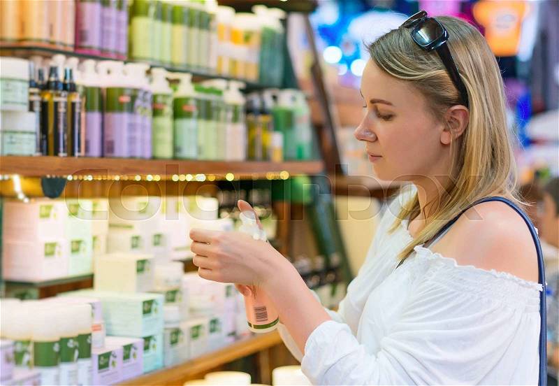Young woman choosing cosmetic cream in beauty shop, stock photo