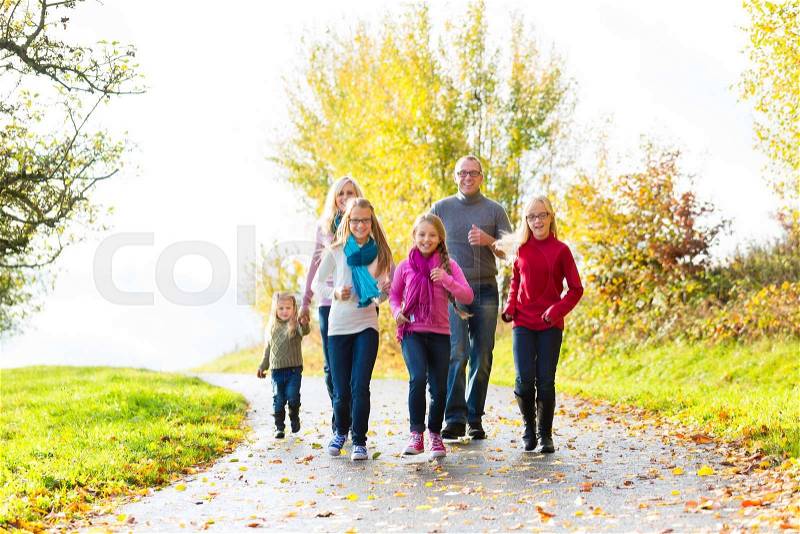 Girls going ahead at family walk through the park in fall or autumn, stock photo
