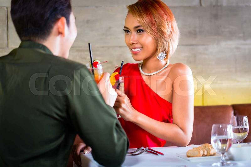 Asian couple drinking cocktails in fancy bar, stock photo