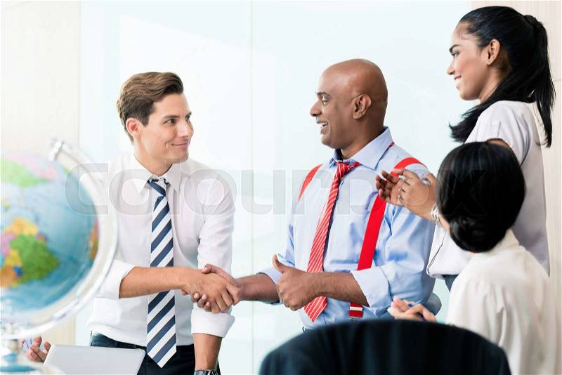 Business handshake in meeting, team of Chinese, Indian and Caucasian ethnicities , stock photo