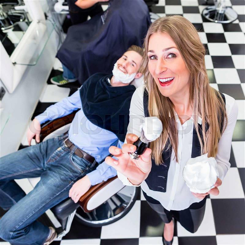 Barber posing in her shop looking right into the camera, stock photo