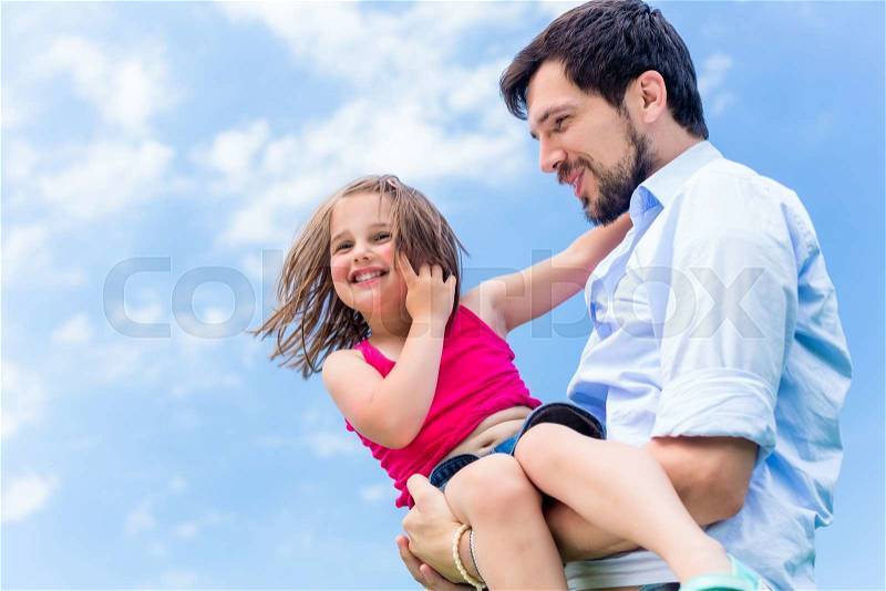 Father carrying daughter in his hands protecting her, stock photo