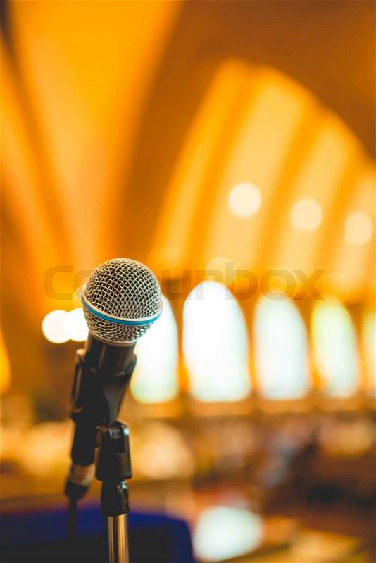 Microphone in concert hall or conference room with defocused bokeh lights in background, stock photo