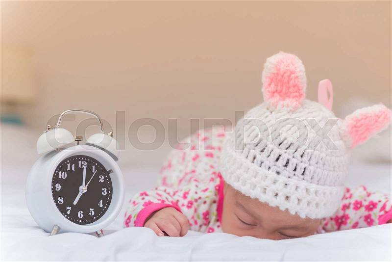 Cute baby girl and alarm clock wake up in the morning, stock photo