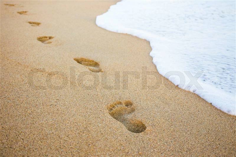 Close up of footprints in the sand and sea wave, stock photo