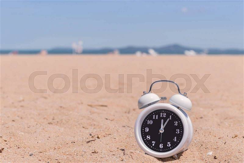 Classic analog clocks in sand on the beach, stock photo