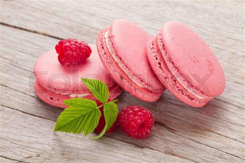 Pink raspberry macaron cookies on wooden table background, stock photo