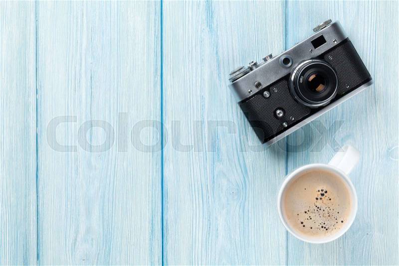 Travel camera and coffee cup on wooden table. Top view with copy space, stock photo