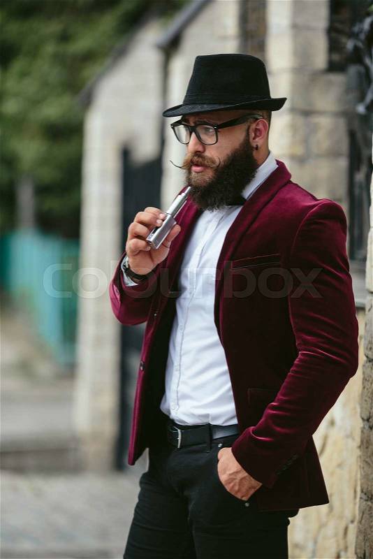 Rich man with a beard smokes electronic cigarette, stock photo