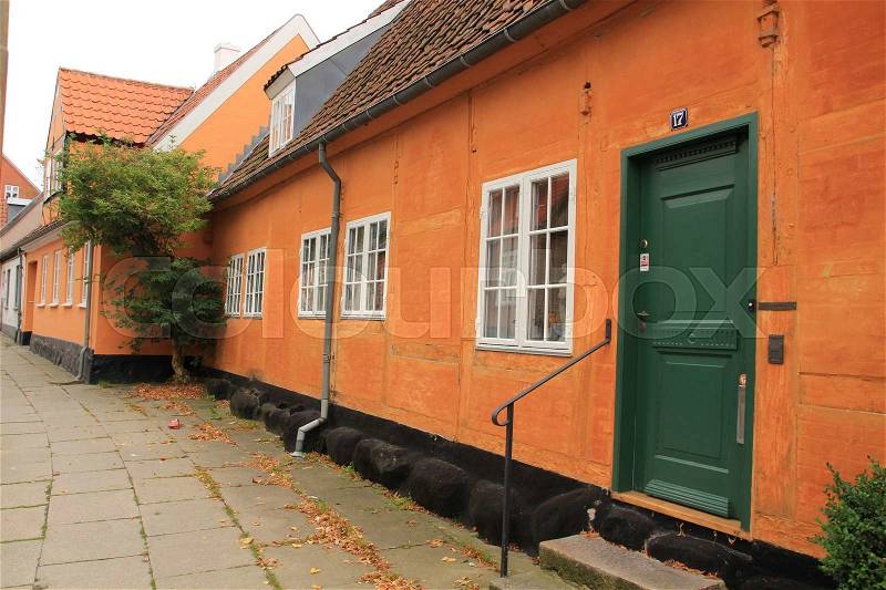One of the streets with painted orange houses in the city Roskilde in Denmark in the summer, stock photo