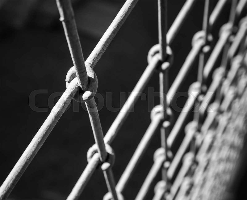 Rough steel fence macro fragment over black blurred background, stock photo