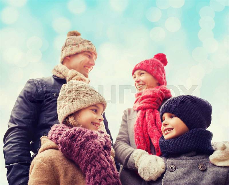 Family, childhood, season and people concept - happy family in winter clothes over blue lights background, stock photo
