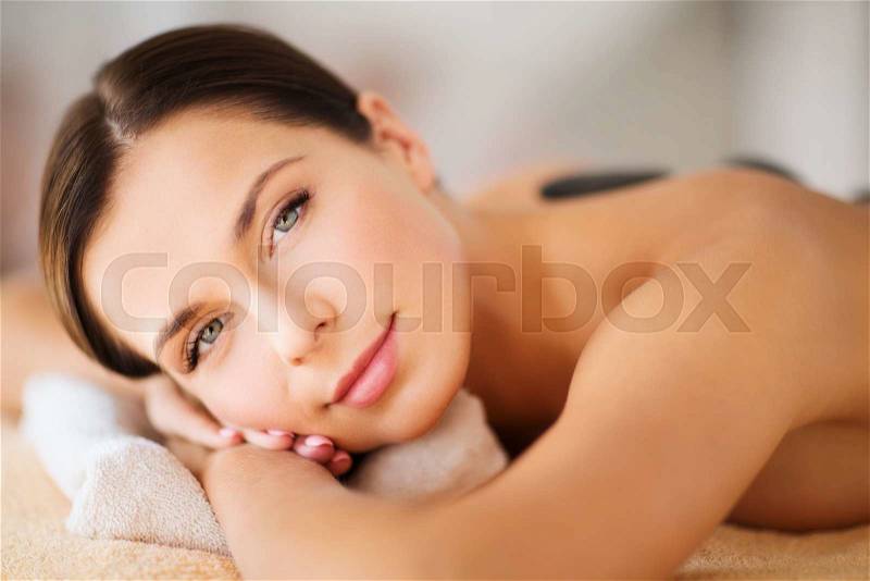 Health and beauty, resort and relaxation concept - beautiful woman in spa salon with hot stones, stock photo