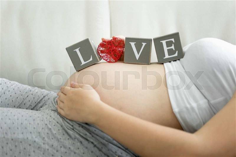 Conceptual shot of word Love spelled on blocks on pregnant women tummy, stock photo