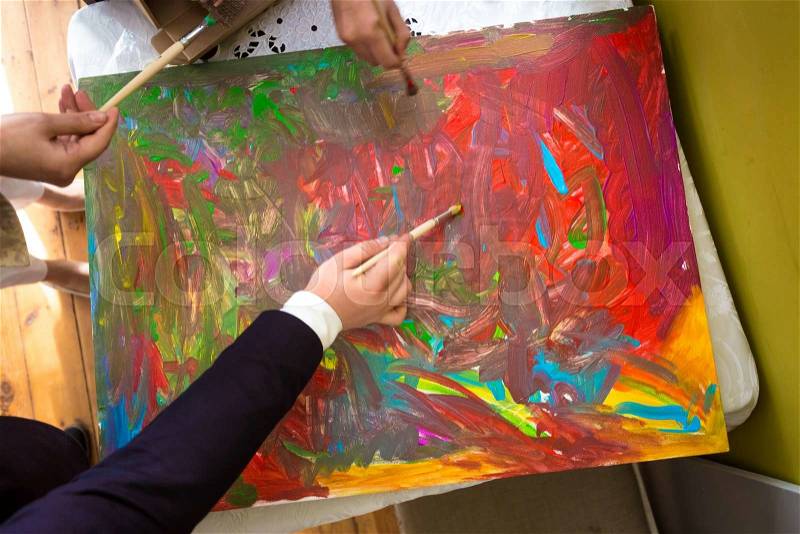 Closeup photo of people mixing colorful paints on canvas, stock photo